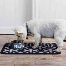Load image into Gallery viewer, White dog eating from a metal bowl labeled 'Narla' on a patterned mat.