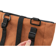 Load image into Gallery viewer, Close-up of a brown canvas bag with black adjustable straps and plastic buckles, showing a hand adjusting one of the straps against a white background.