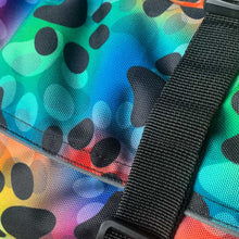 Load image into Gallery viewer, Close-up of a colorful fabric with black paw prints and a black strap.