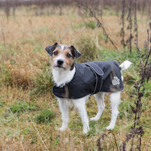 Load image into Gallery viewer, Dog wearing a black coat with paw prints in a grassy field