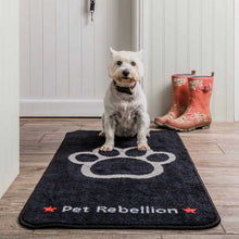 Load image into Gallery viewer, Dog standing on a 'Pet Rebellion' mat with red boots in the background