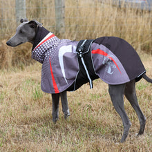 Load image into Gallery viewer, A greyhound dog standing in dry grass wearing a protective dog coat. The coat is primarily dark gray and black with white polka dots, red accents, and a white graphic of a dog wearing a coat.
