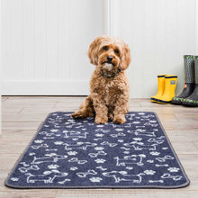 Load image into Gallery viewer, Dog sitting on a blue mat with paw prints and dog illustrations, wearing yellow and green boots in the background.