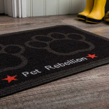 Load image into Gallery viewer, Black doormat with paw prints and 'Pet Rebellion' text on a wooden floor.
