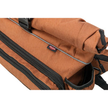 Load image into Gallery viewer, Close-up of a brown VRAKE bag with black zippers, a gray piping detail, and a small red and white VRAKE logo tag.
