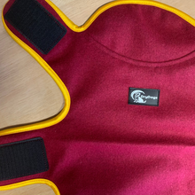 Load image into Gallery viewer, Red pet coat with yellow trim and a visible brand logo on a wooden surface
