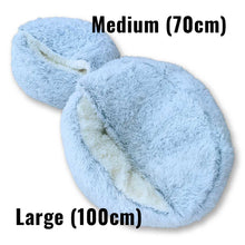 Load image into Gallery viewer, Two plush pet beds shown on a white background with text labels indicating sizes: a smaller Medium (70cm) and a larger Large (100cm). The beds are light blue with cream-colored plush interiors.
