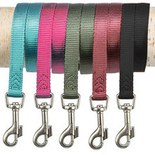 Load image into Gallery viewer, Five pet dog leashes in different colors (teal, pink, olive green, dusty rose, and black) are shown hanging from a light-colored wooden dowel. Each leash has a silver metal clip at the bottom with the brand name 'TRIXIE' visible on the clasp.

