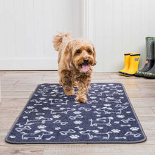 Load image into Gallery viewer, Dog walking on a blue mat with white dog and bone patterns, with yellow and green boots in the background.
